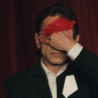 A person with a white shirt and a blazer covers half of their face, their palm, and part of the forehead has a red thick line.