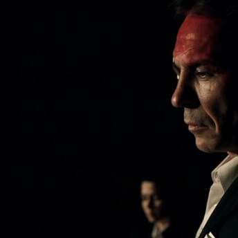 Profile shot of a man with his forehead painted in red.