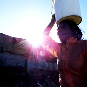 A person walking with a bucket on the top of her head.