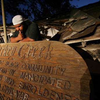 A man leans on a big wooden carved plate.
