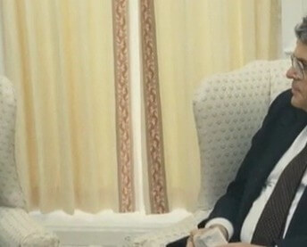 Still from My Favorite Neoconservative. Two men sit across from each other in armchairs.