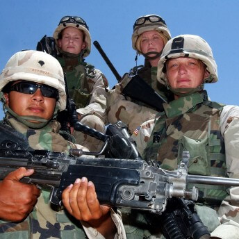 Still from Lioness. Low angle shot of a group of four soldiers in uniforms and with guns.