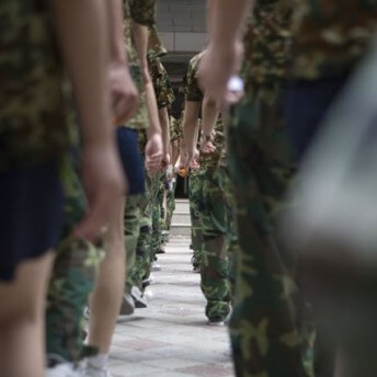 Still from Web Junkie. Two side-by-side lines of young boys dressed in camo. Color photograph.