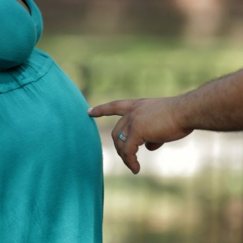 Still from Tough Love. Close-up of a hand pointing at a pregnant belly.