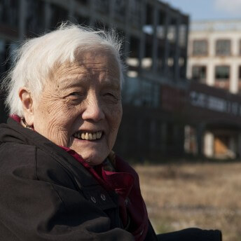 Stil from Grace Lee American Revolutionary: The Evolution of Grace Lee Boggs. Grace Lee Boggs is looking directly at the camera and smiling, she has white short hair, and is wearing a black warm jacket.