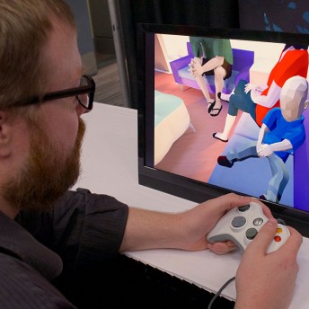 A still from Thank You For Playing. Ryan Green holds a white game controller and is seated in front of a small monitor.