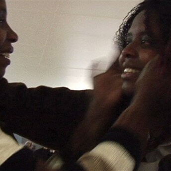 Still from Pushing The Elephant. Two people, face to face, smile at each other as they touch the face of the other.