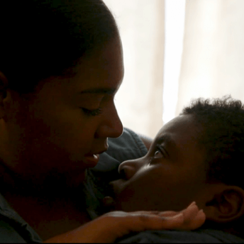 Still from Tre Maison Dasan. A woman holds a boy tenderly in her arms.