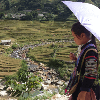 Still from Along the Line. A young girl is walking down a hill, she is holding an umbrella.