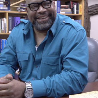 A man looking away from the camera and giggling.