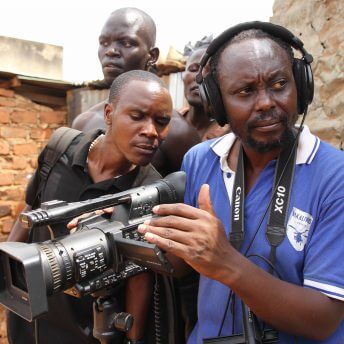 Still from Once Upon a Time inUganda. A film crew of four are gathered by a camera. Two of the four look at the camera screen.