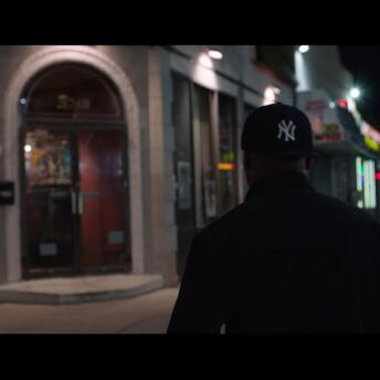 A man walking away from the camera wearing a Yankees cap.