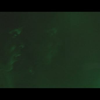 A profile shot of two persons with a green light on them.