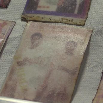 Still from Number 387. A few washed out photographs sit on a paper towel.