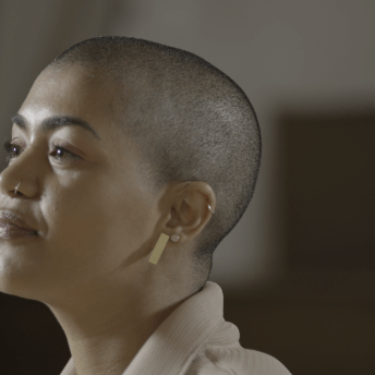 Still from Milisuthando (working title). A woman is looking off camera, smirking.