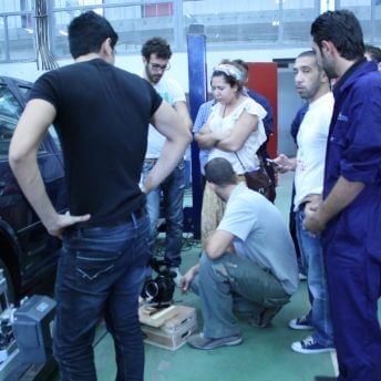 A group of people standing next to a car. Color photograph.
