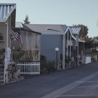 Full shot of a woman coming out from her house. The house is on a street where houses are in line.
