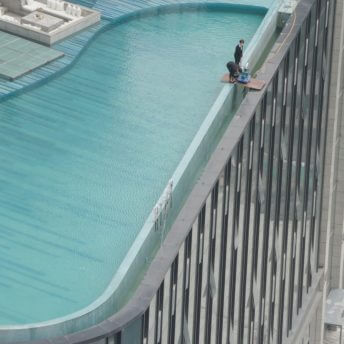 Still from Ascension. Two people are working on the top of a skyscraper.