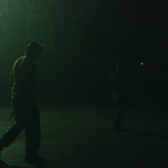 Still from Storming. A person walks on a dark road.