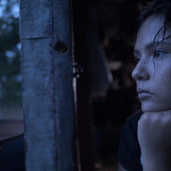 Still from Once Upon a Time in Venezuela. The close-up of a woman stares outside with her hand under her chin.