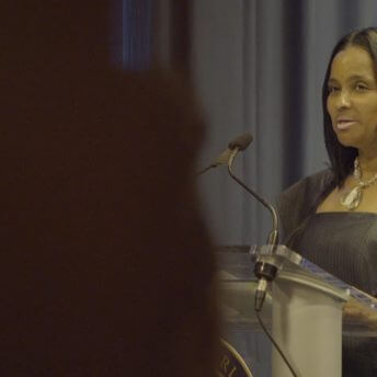 Danielle Metz talking in front of a podium.