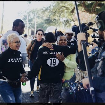 People hugging in front of a sound person.