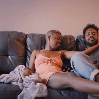 A still from The Dilemma of Desire. Two people sitting on a brown couch.