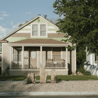 Still from Sanctuary. A small house with a tree in the front yard and a car in the driveway.