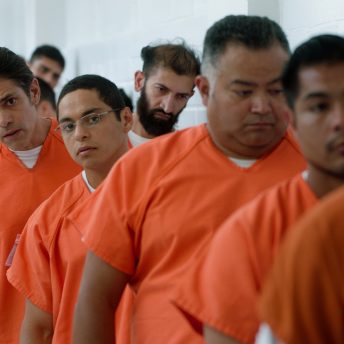 Men in orange prison uniforms are in a line.