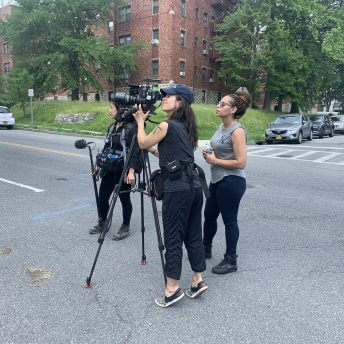 Three crew members are working with a camera in the middle of the street.