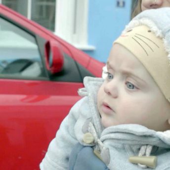 Still from Is There Anybody Out There? Close-up of Ella Glendining's infant son River. He is wearing a hat and a thick light blue coat.