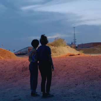 Silvia and Beba's silhouettes are pictured in front of a train at sundown.