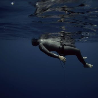 Long shot of a woman in a diver suit with the face out of the water