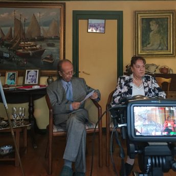 Director grandparent’s being filmed in their living room reading a text.