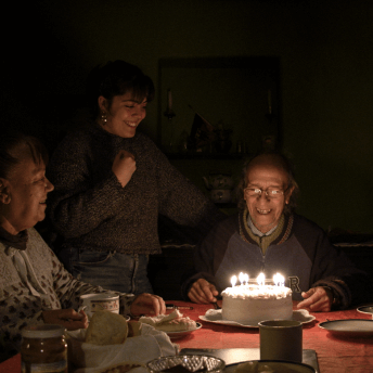 Director Gabriela Pena at her grandfather’s birthday with her grandmother and a cake with candles.