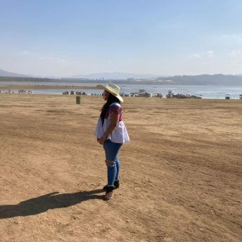 Olimpia Coral wearing a cowboy hat and boots in a rural landscape in Huauchinango, Puebla, Mexico.
