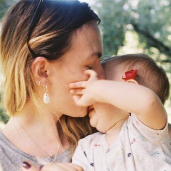 Lina is kissing her baby daughter on the forehead.