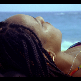 Close up to Beba laying down, in the background the ocean is visible