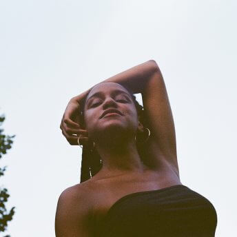 Low angle shot of Beba, placing her arm behind her head and wearing a black top