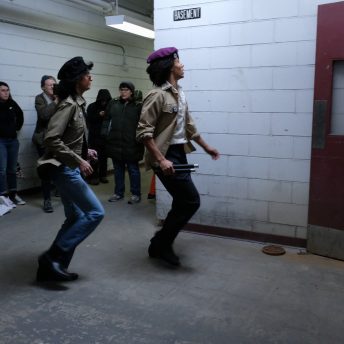 Two actors dressed as members of the Young Lords Party walking very fast