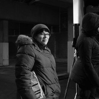 Portrait of a crew member wearing a puffed jacket, a beanie and holding papers of the production
