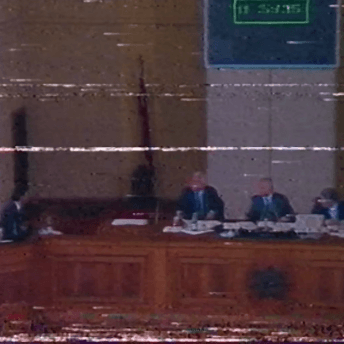 Damaged VHS archive image of four people at the wooden Parliament podium