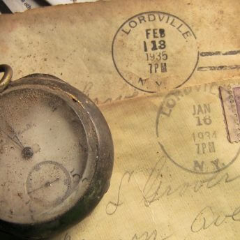 Still from Lordville. A closeup of a dirt encrusted antique watch that sits on top of a yellowed old letter with a postmark dated to February 13, 1939, Lordville New York.