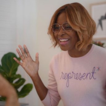 Still from Breaking the News Film. Editor-at-large Errin Haines is smiling directly at the camera in a pink sweatshirt that reads "Represent."