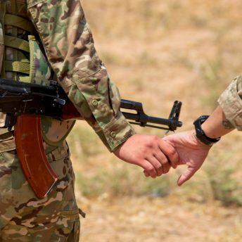 An image showing two women guerrillas in front line holding hands.