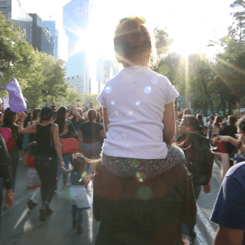 A mother carries her daughter on her shoulders during a protest against women violence on November 25, 2017.