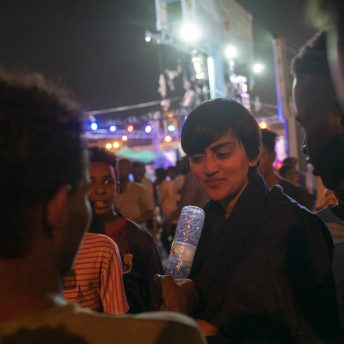 A group of Sudanese protestors interview the director using a water bottle as a microphone.