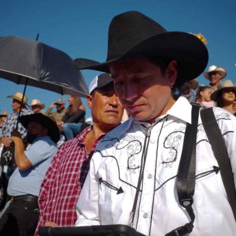 Director Efraín looks at monitor in the stands at a jaripeo.