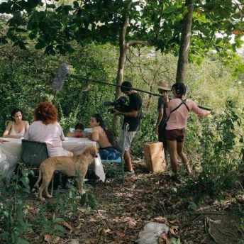 The Villanueva family sit at a table to discuss the script while a cinematographer, sound person and facilitator work behind the scenes.