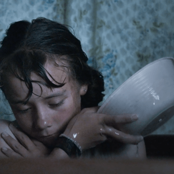 A little girl pours water on herself in a bath.